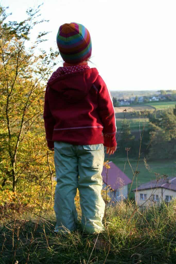 małe dziecko patrzy z pagórka na miejscowość poniżej, jesień