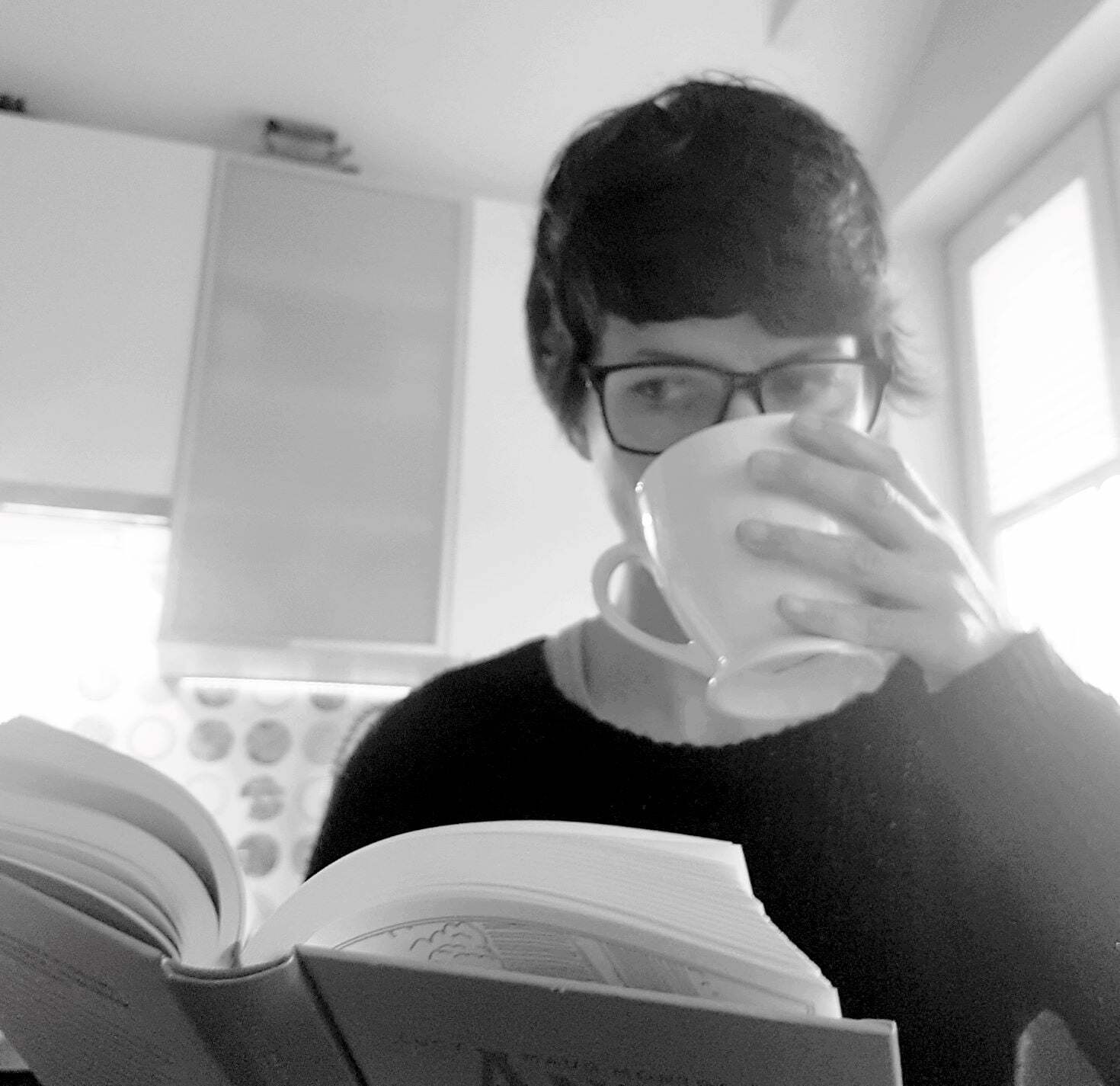 czarno-białe zdjęcie jak piję kawę i czytam książkę