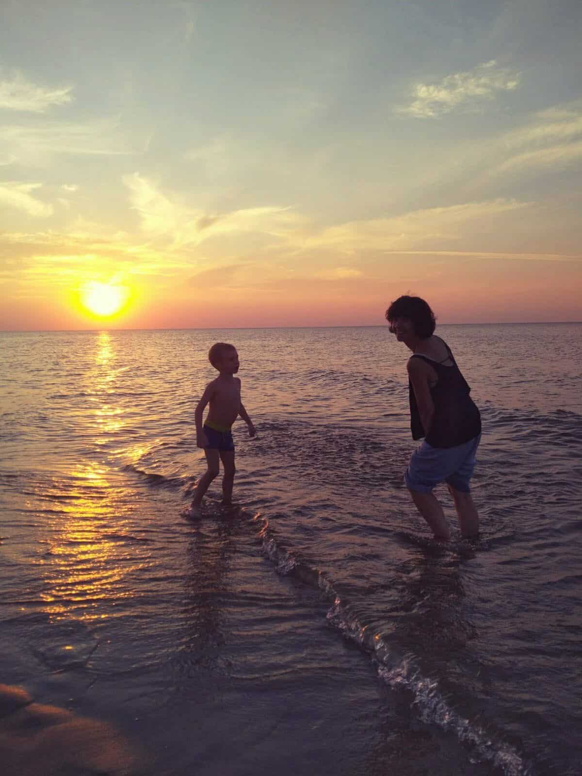 wychowanie - radosny obrazek znad morza, mama i dziecko razem się bawią