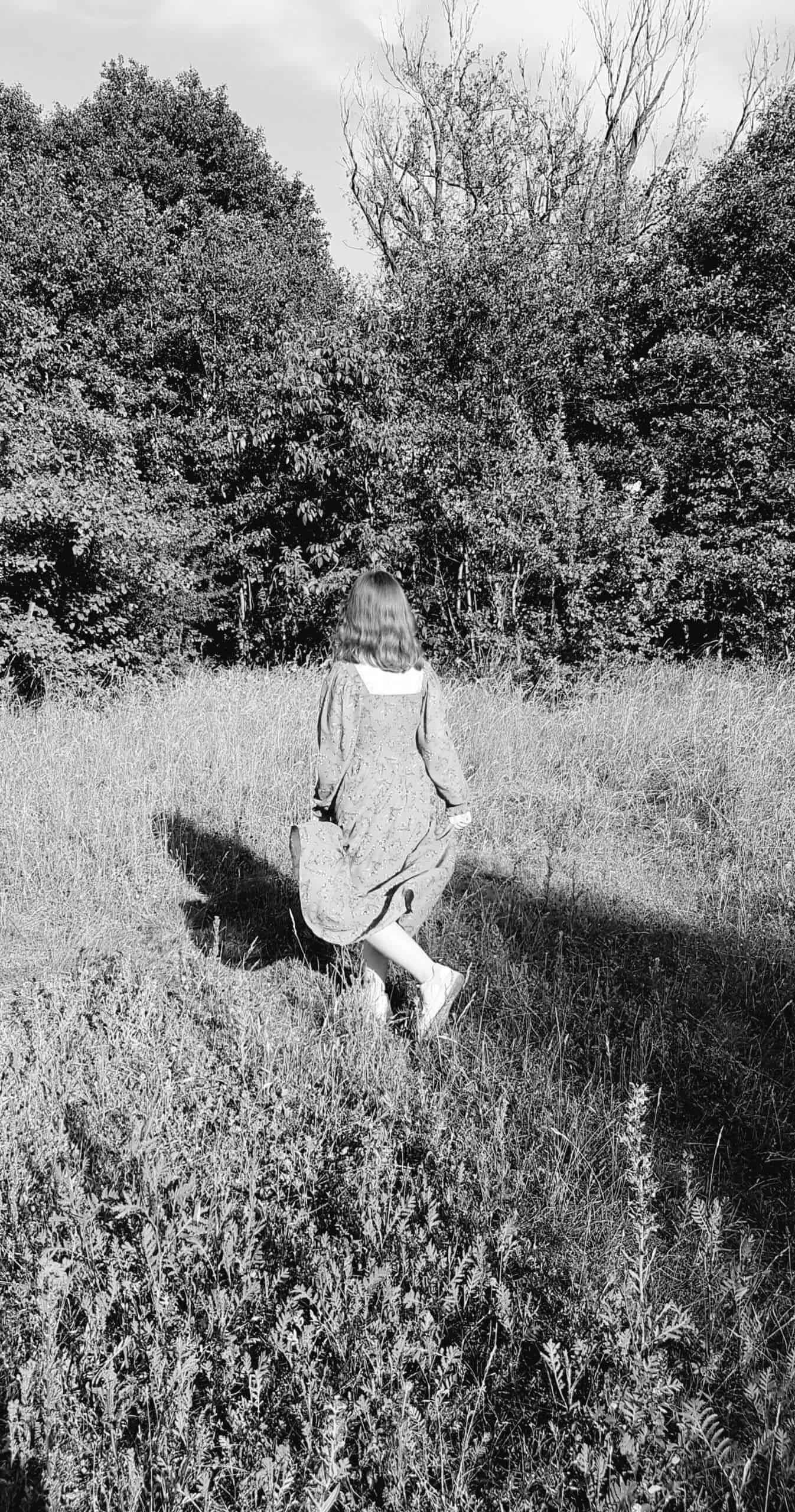 opowieści rodzinne - zdjęcie dziewczyny biegnącej przez łąkę, czarno - białe