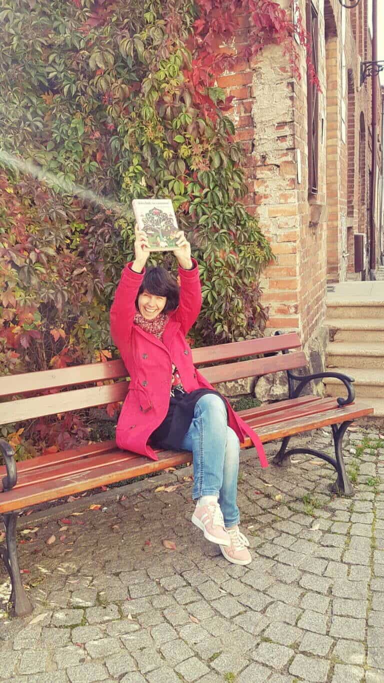 o czytaniu - ja na ławce w mieście, jesień, z uśmiechem pokazuję kupioną książkę