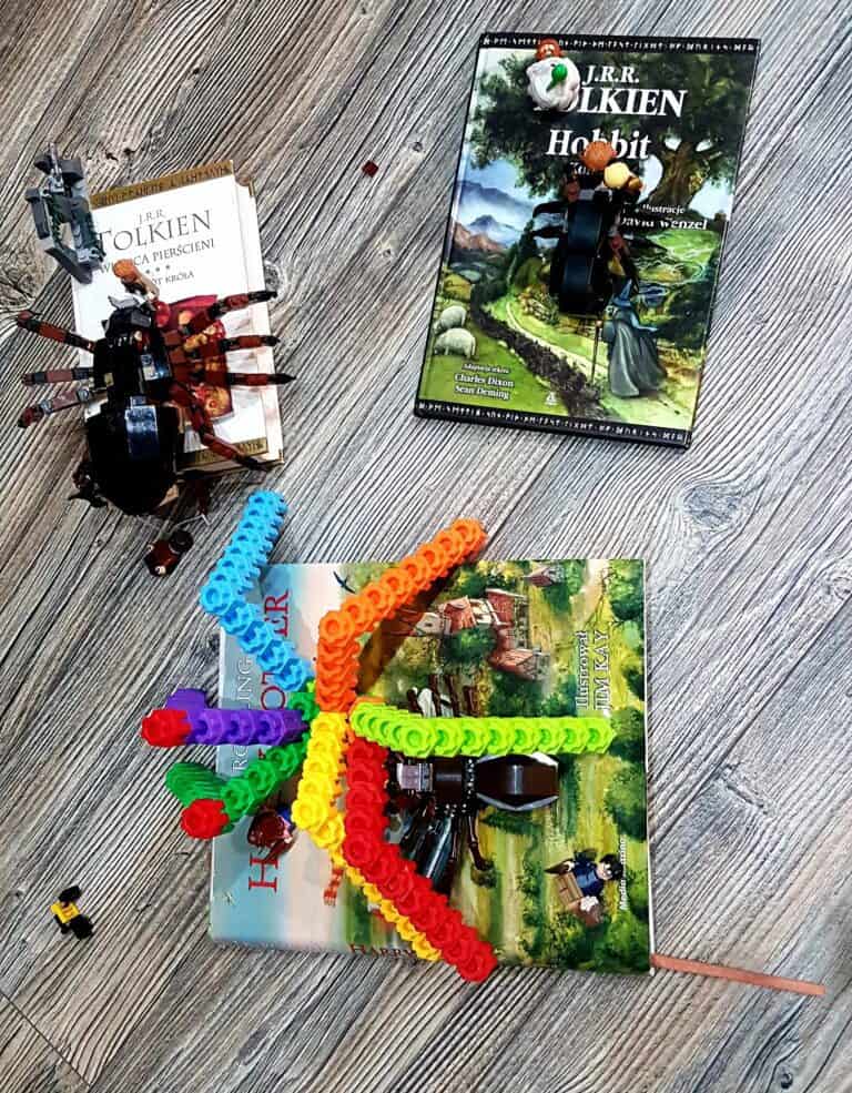 książki z serii władca pierścieni i hobbit, naokoło poustawiane zabawki pasujące tematycznie do książek